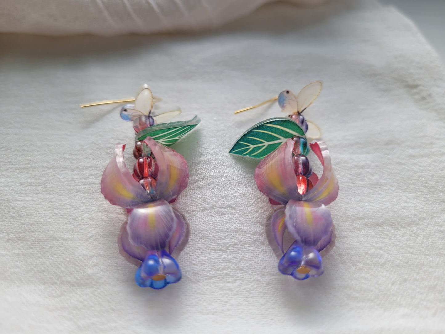Nature-inspired handmade iris and butterfly earrings with delicate gold-tone hooks on a white background.