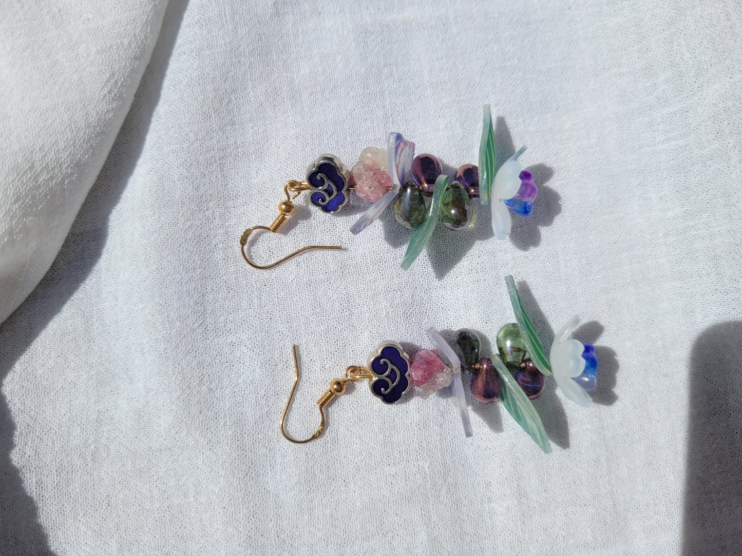 Earrings butterfly, floral and leaves details shaped with Cloisonne cloud-shaped beads on a light background