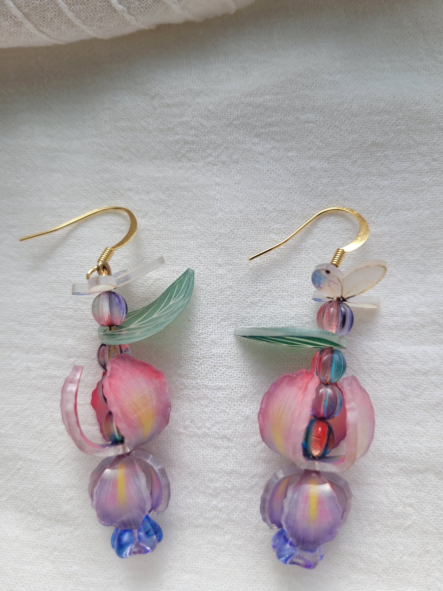 Nature-inspired handmade iris and butterfly earrings with delicate gold-tone hooks on a white background.