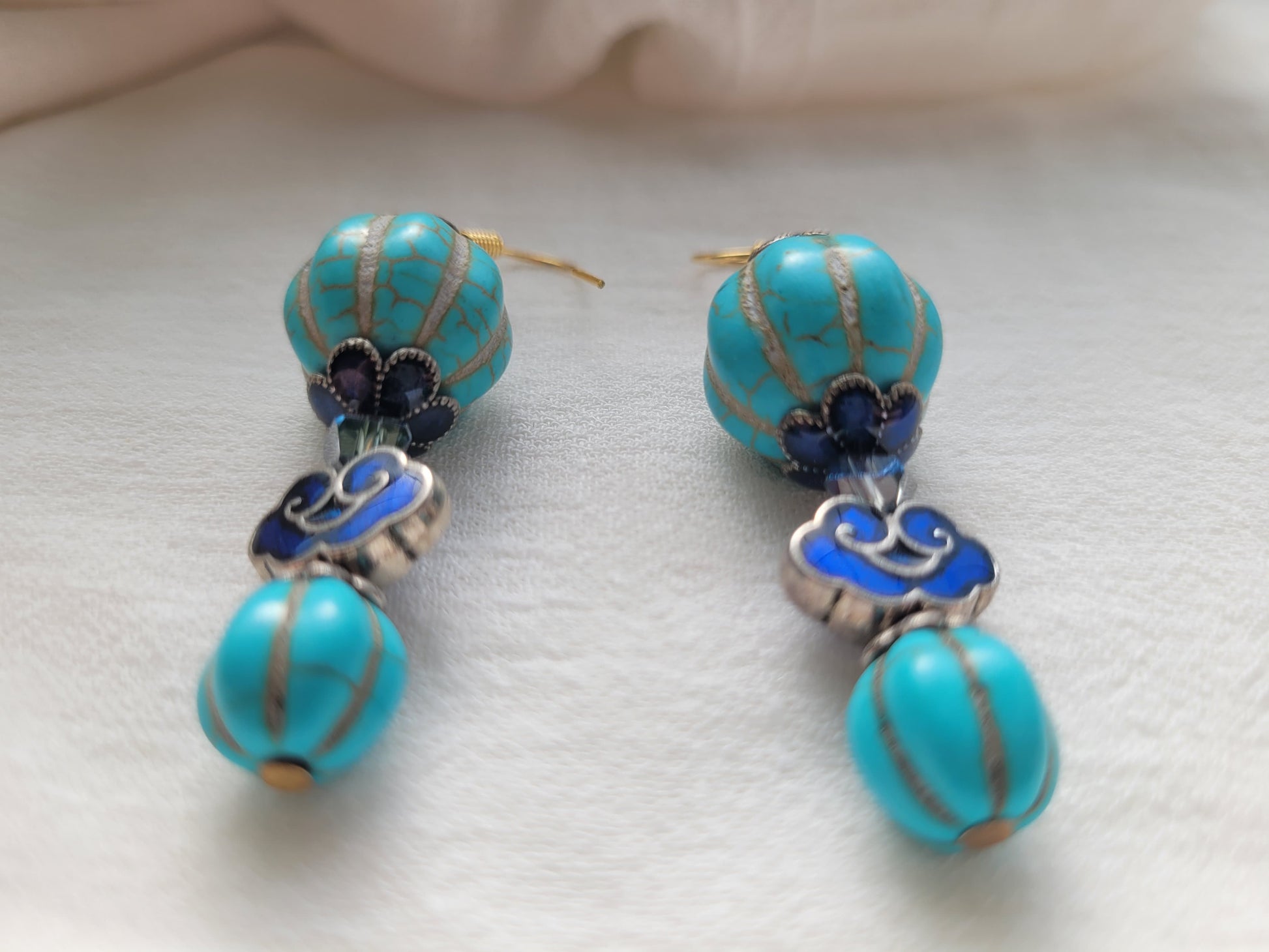Pair of turquoise earrings with blue accents on a light background