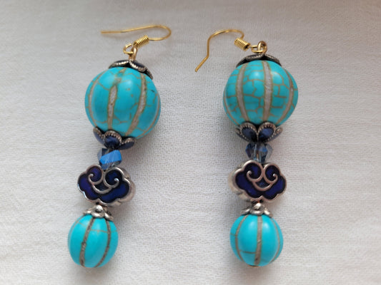 Pair of earrings with turquoise beads and decorative elements on a light background
