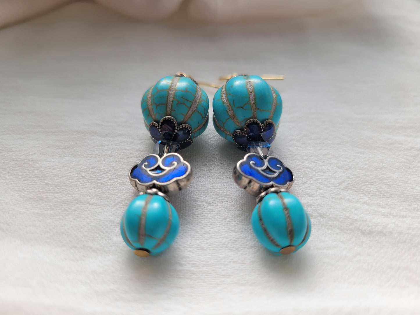 Turquoise beaded earrings with silver and blue accents on a light background