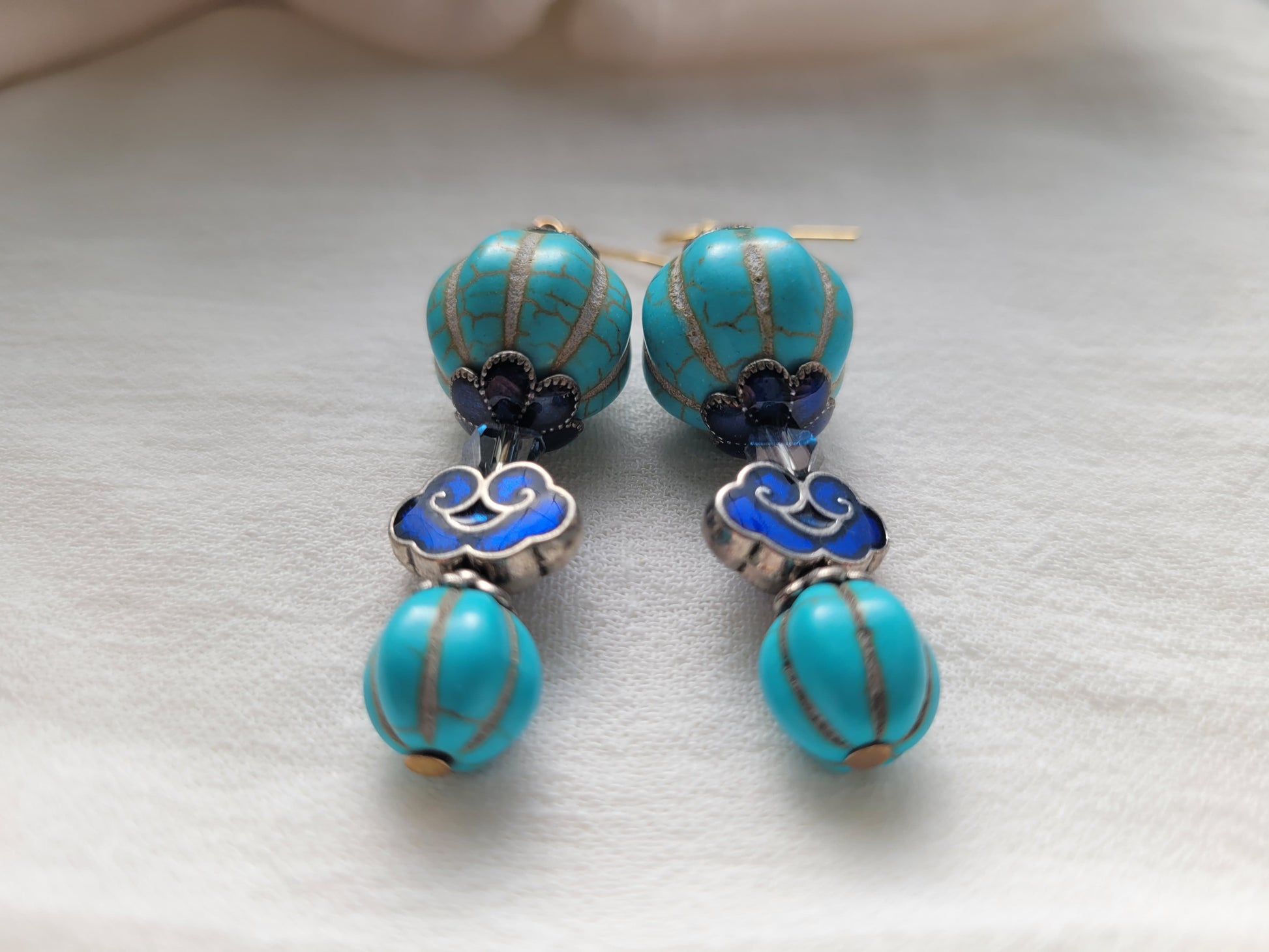 Turquoise beaded earrings with silver and blue accents on a light background