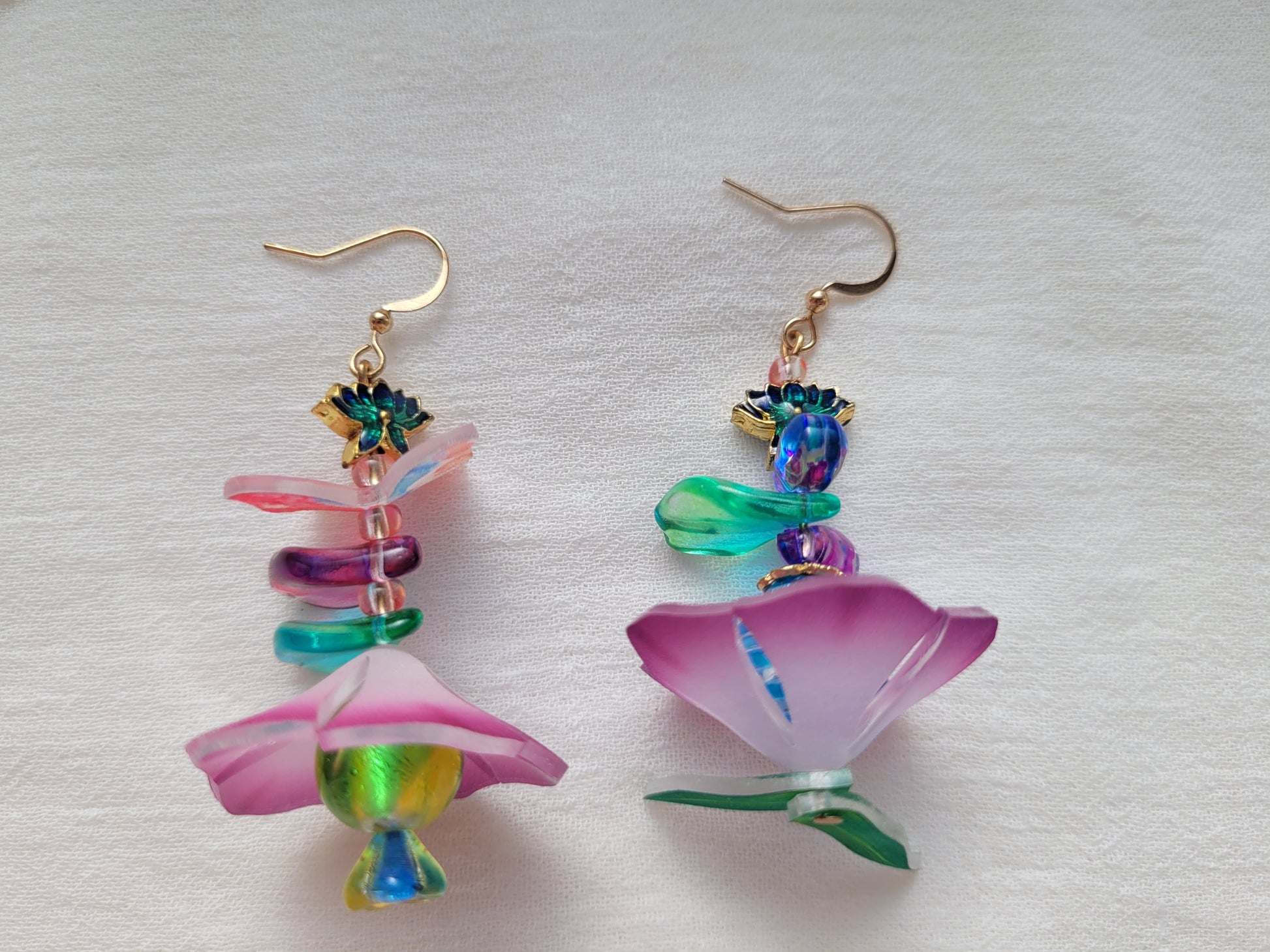 Colorful flower-shaped earrings on a white fabric background