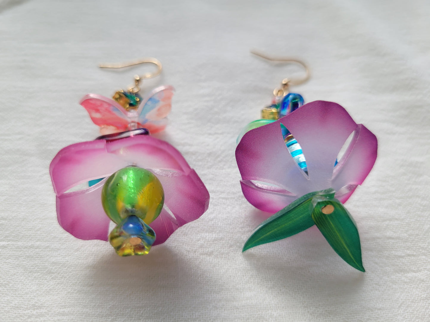 Colorful flower-shaped earrings on a white fabric background