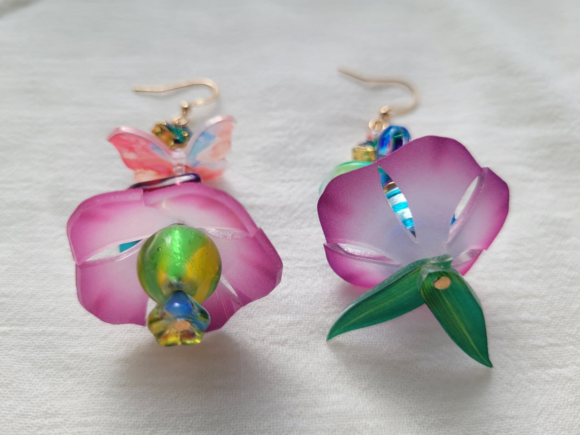 Colorful flower-shaped earrings on a white fabric background