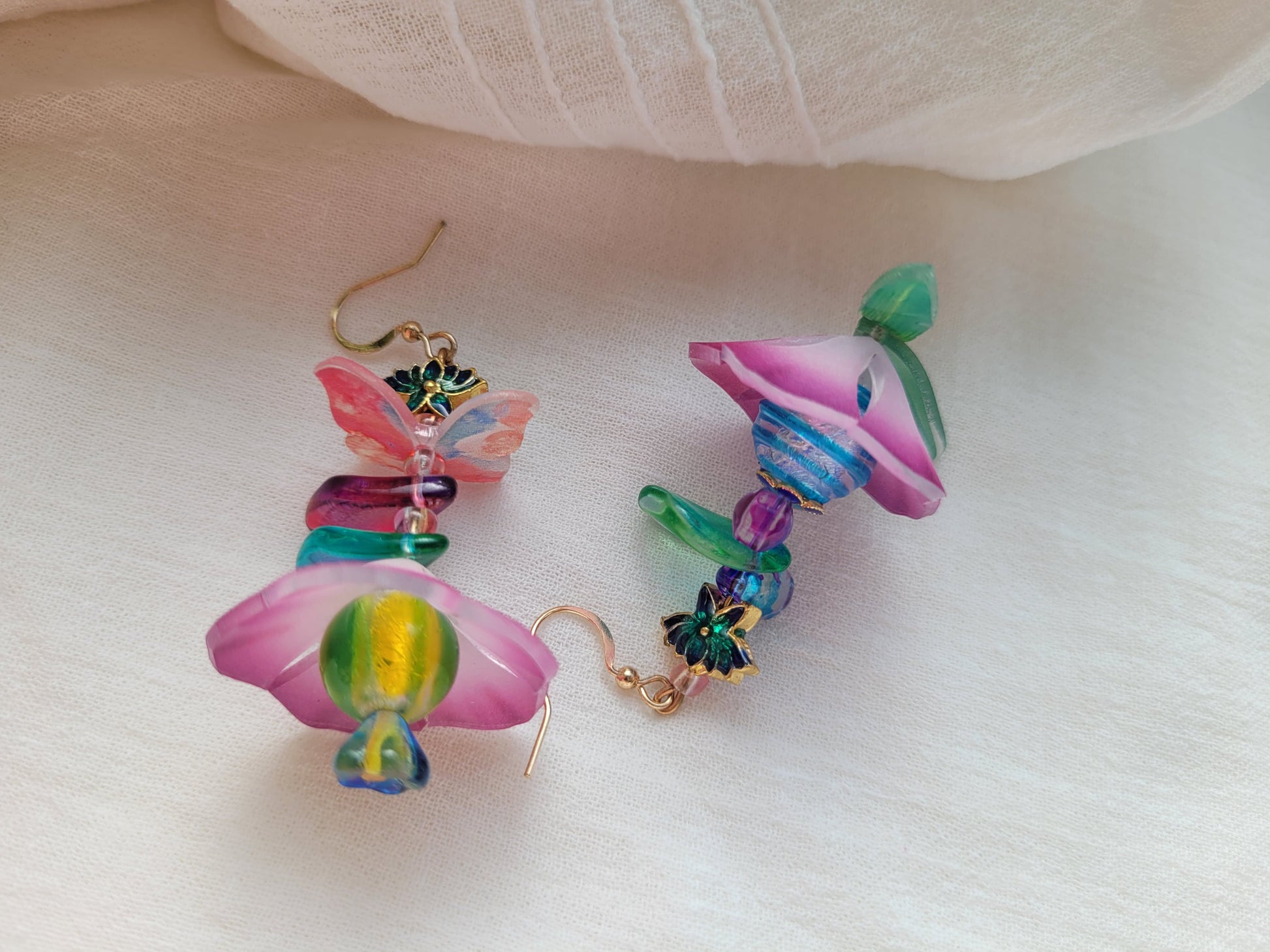 Colorful flower-shaped earrings on a white fabric background
