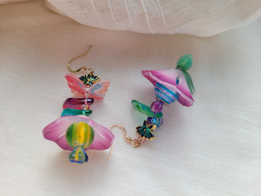 Colorful flower-shaped earrings on a white fabric background
