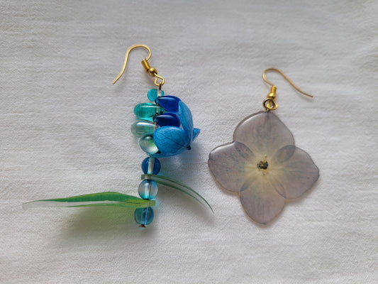 Pair of earrings with natural hydrangea flower and blue beads on a light gray background