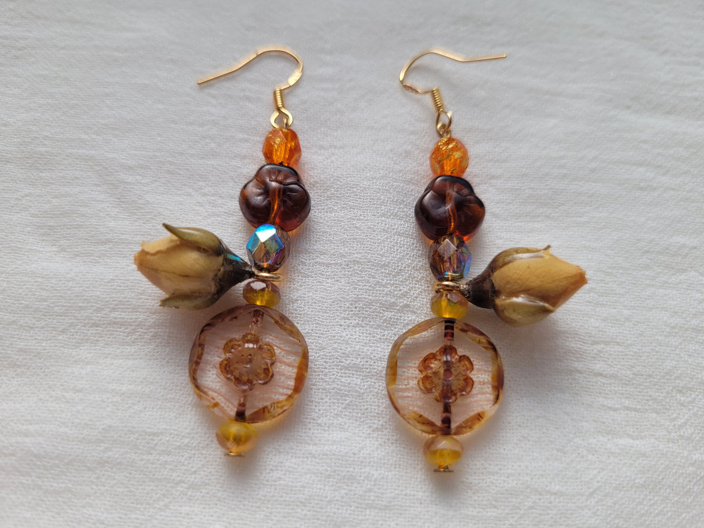 Pair of beaded earrings with natural rose buds on a light gray background