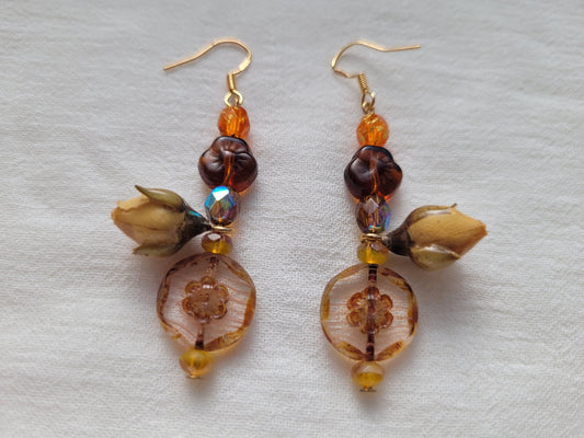 Pair of beaded earrings with natural rose buds on a light gray background
