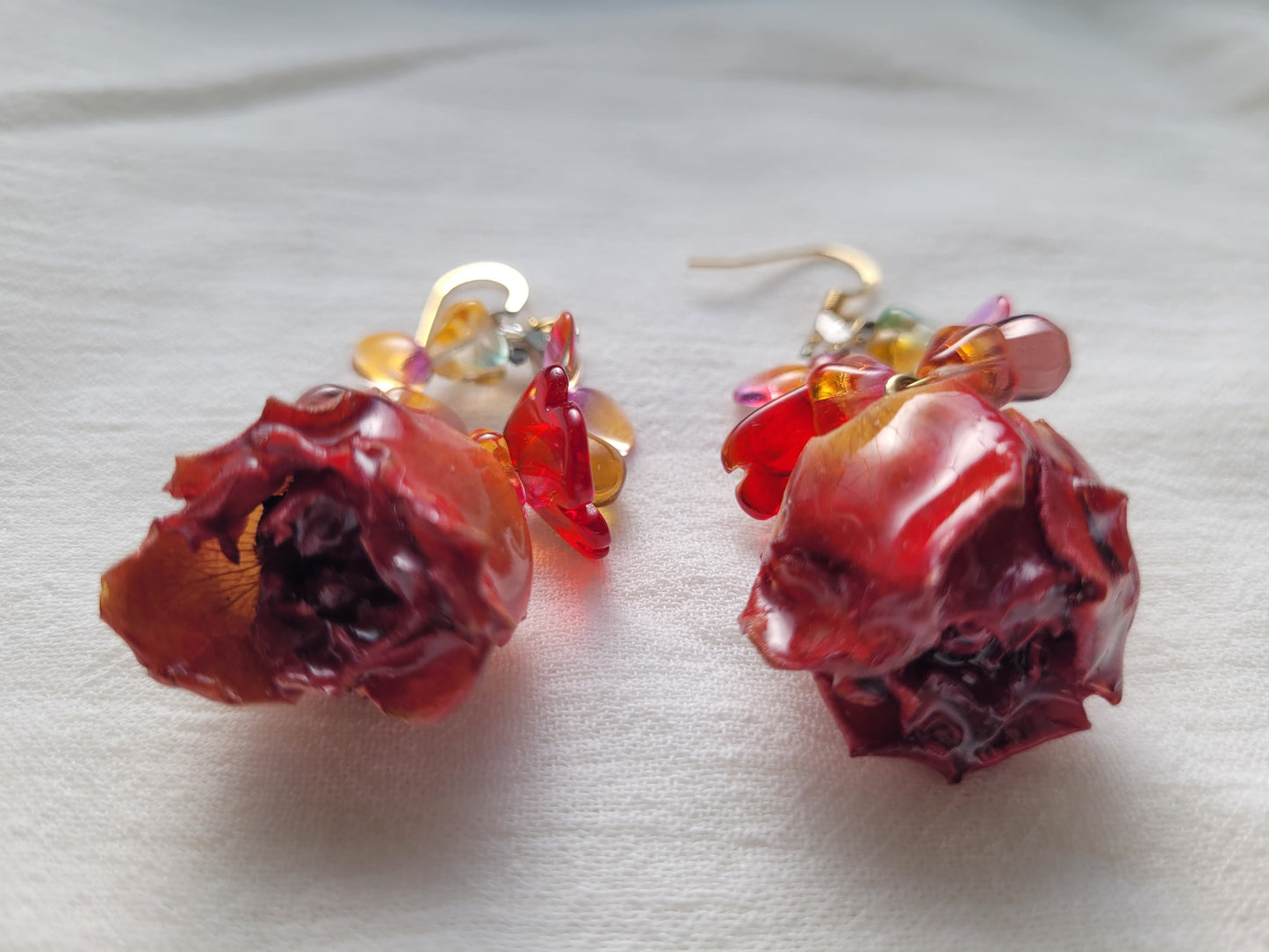 Pair of red rose-shaped earrings on a light background