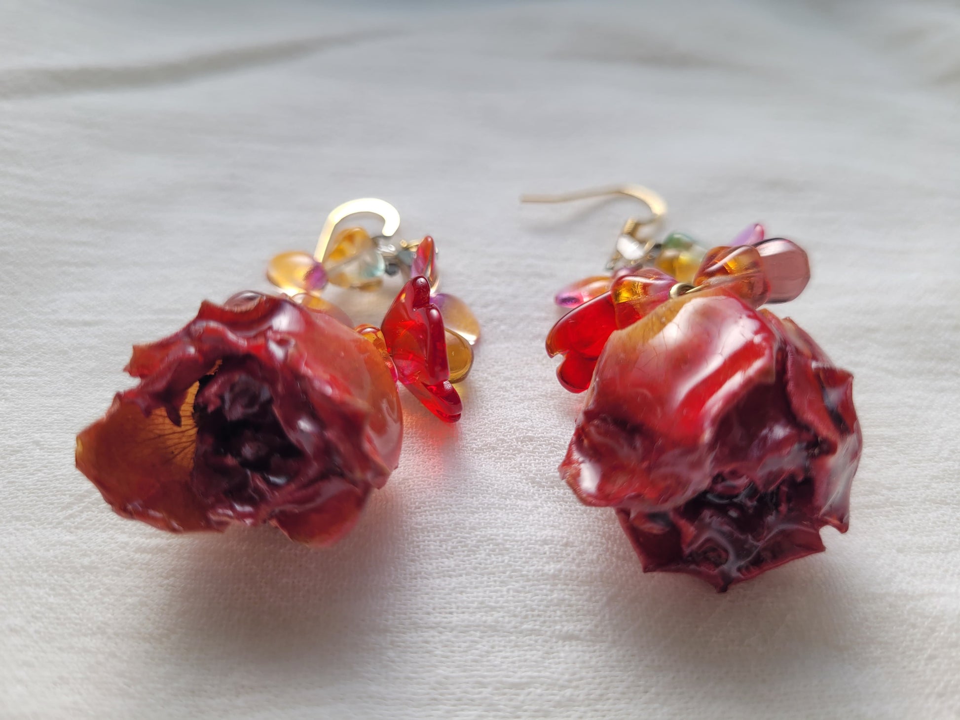Pair of red rose-shaped earrings on a light background
