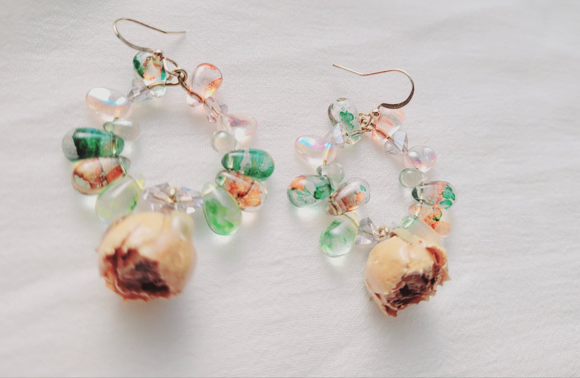 Pair of earrings with natural roses and bead details on a light background