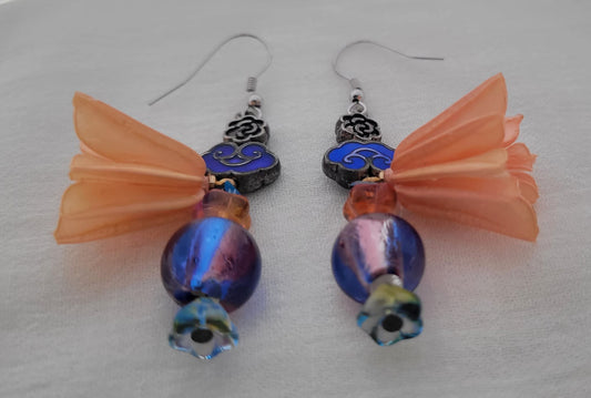 Pair of earrings with blue beads and peach coloured flower decoration on a white background