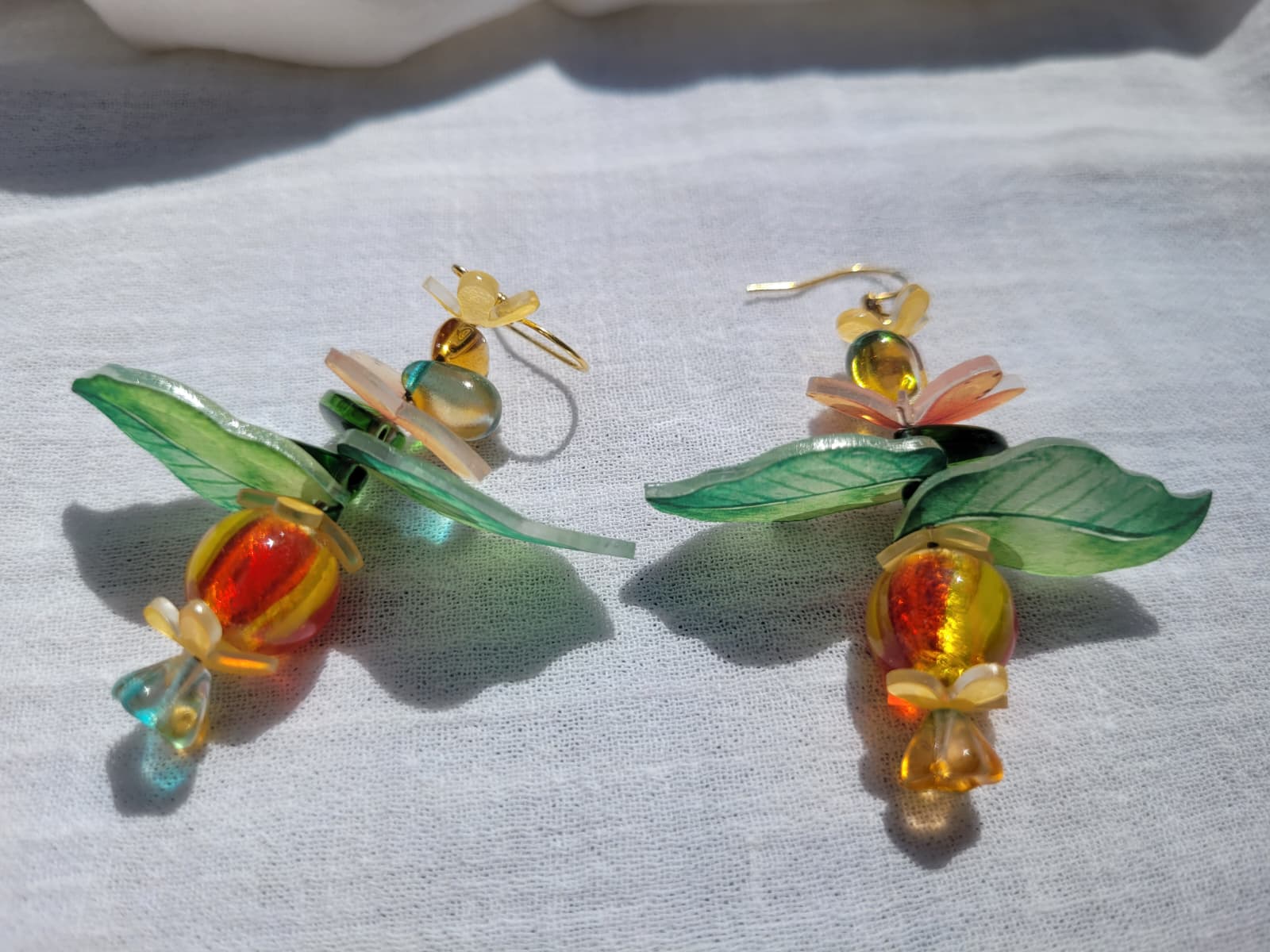 Pair of colorful glass earrings with leaf and flower design, glass czech beads and butterflies on a light gray background