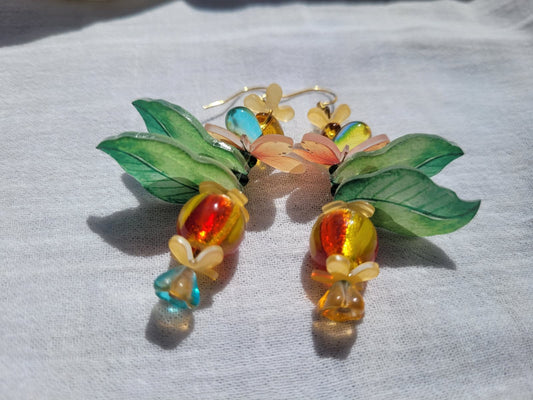 Pair of colorful glass earrings with leaf designs, glass czech beads and butterflies on a light gray background