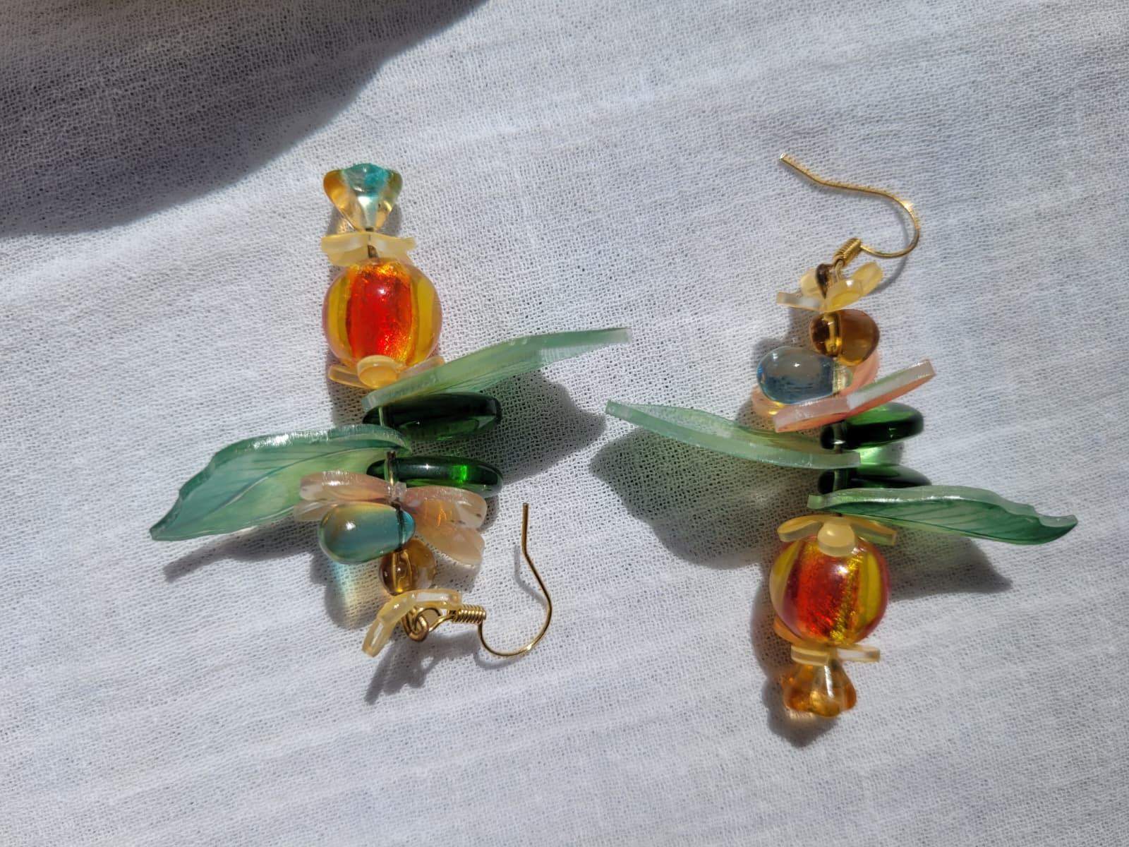 Pair of colorful glass earrings with leaf designs, glass czech beads and butterflies on a light gray background