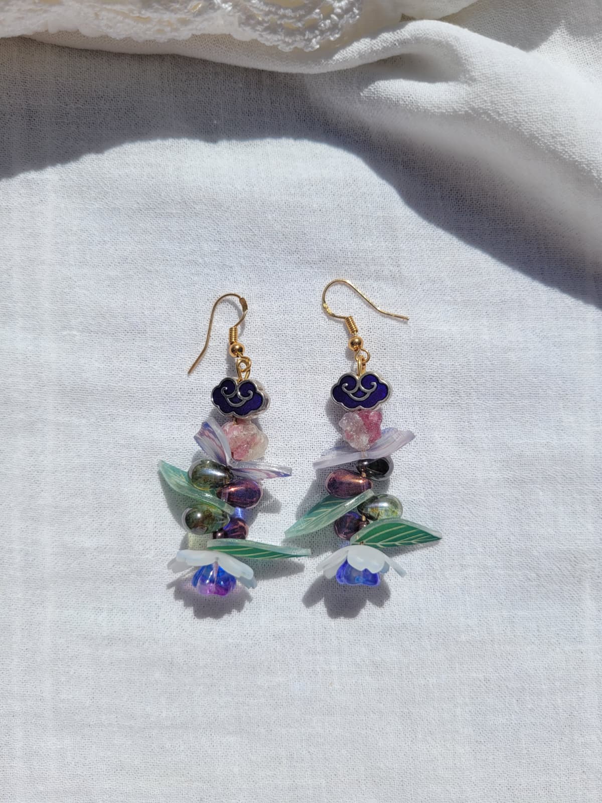 Earrings with butterfly, floral and leaves details, with Cloisonne cloud-shaped beads on a light background