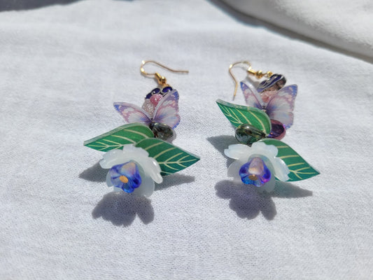 Earrings butterfly, floral and leaves details shaped with Cloisonne cloud-shaped beads on a light background