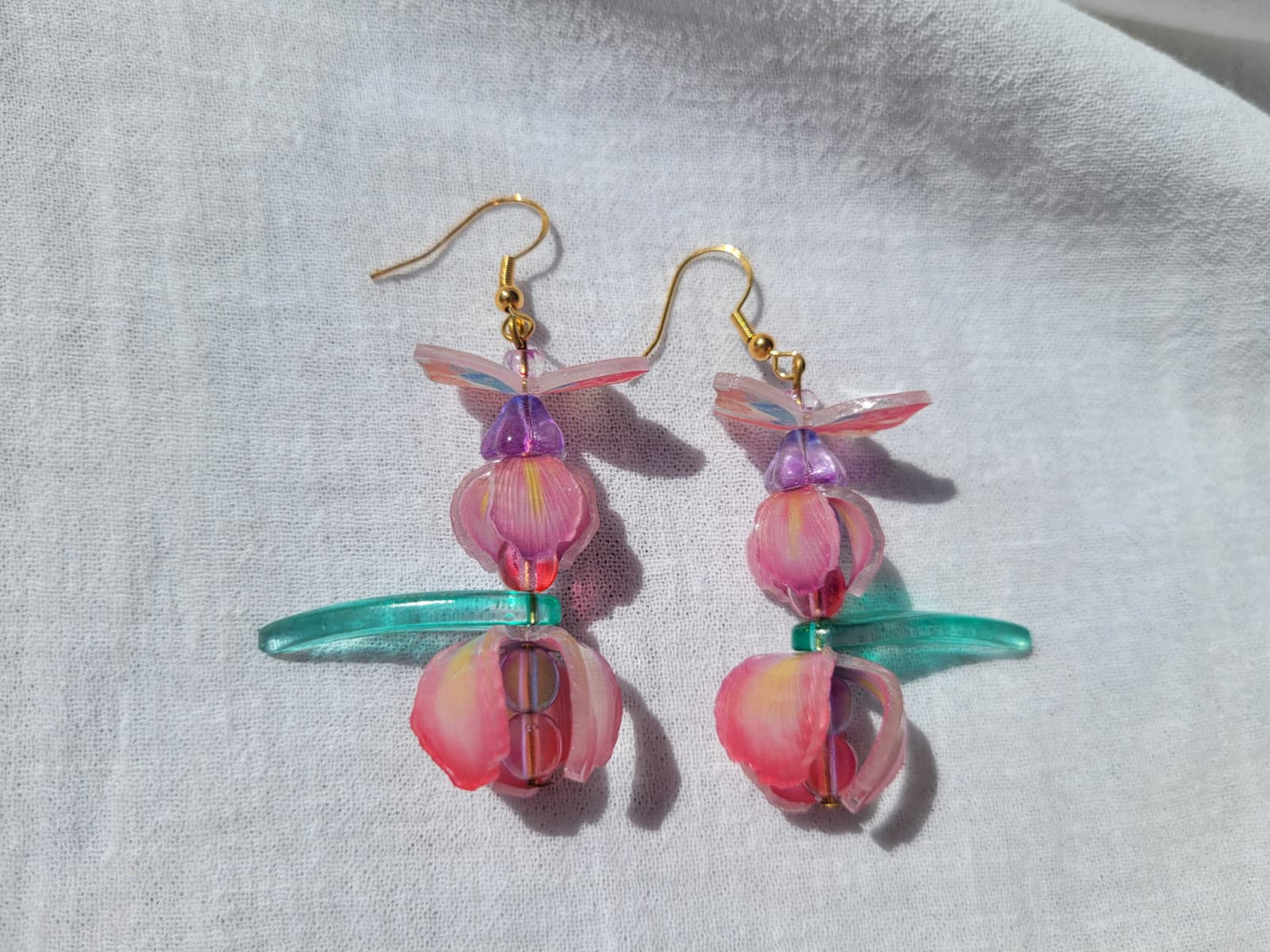  Pink iris-shaped earrings with green leaves and pink butterflies on a light gray background