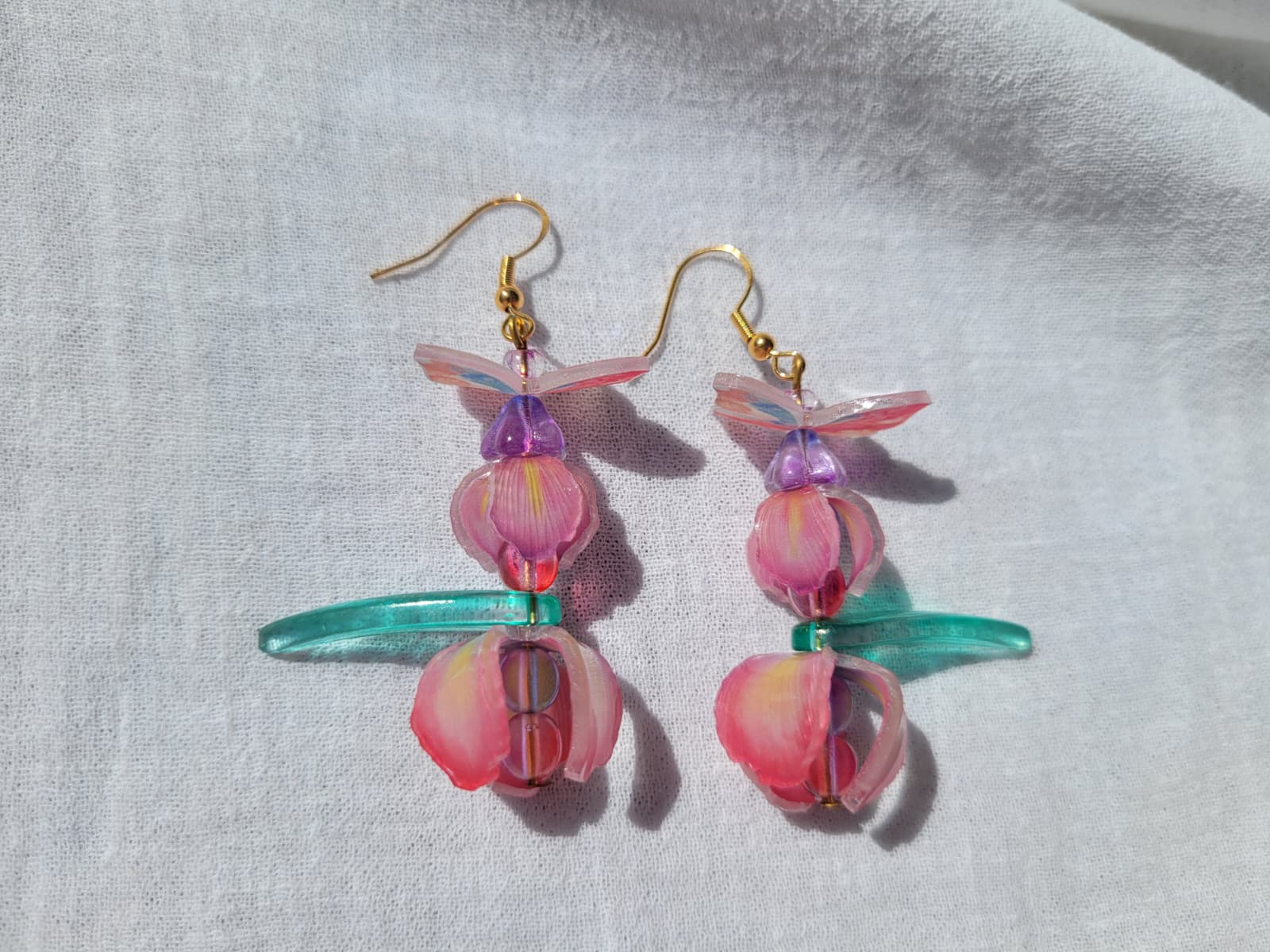  Pink iris-shaped earrings with green leaves and pink butterflies on a light gray background