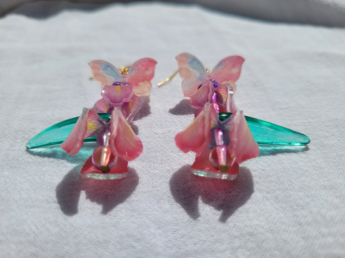  Pink iris-shaped earrings with green leaves and pink butterflies on a light gray background