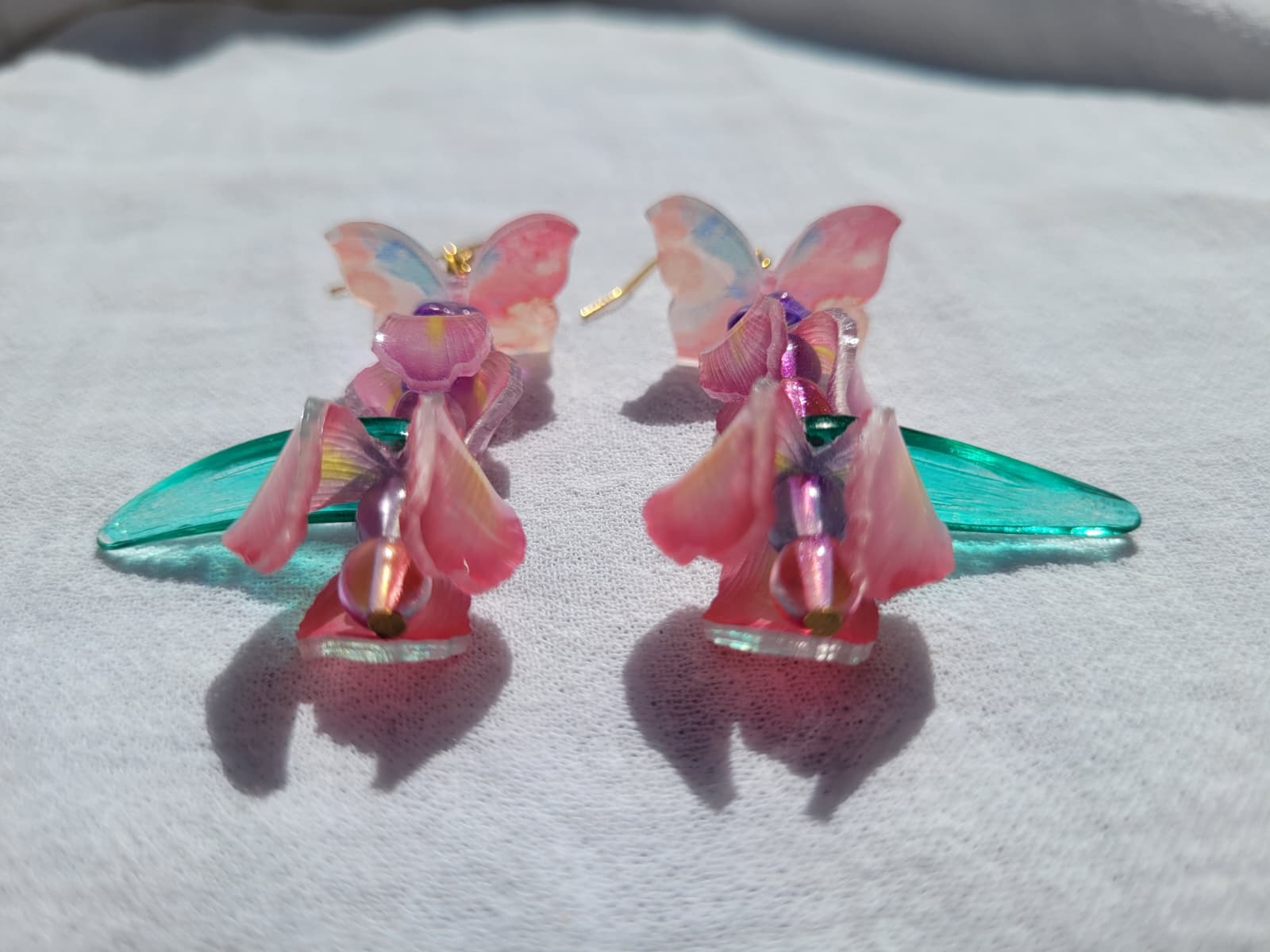  Pink iris-shaped earrings with green leaves and pink butterflies on a light gray background
