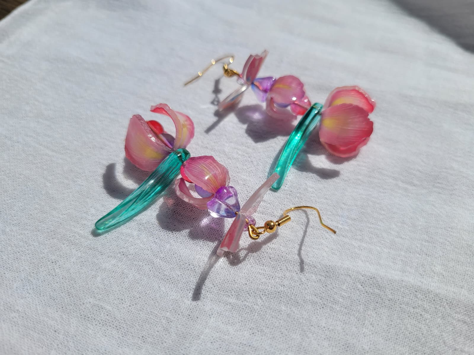  Pink iris-shaped earrings with green leaves on a light gray background