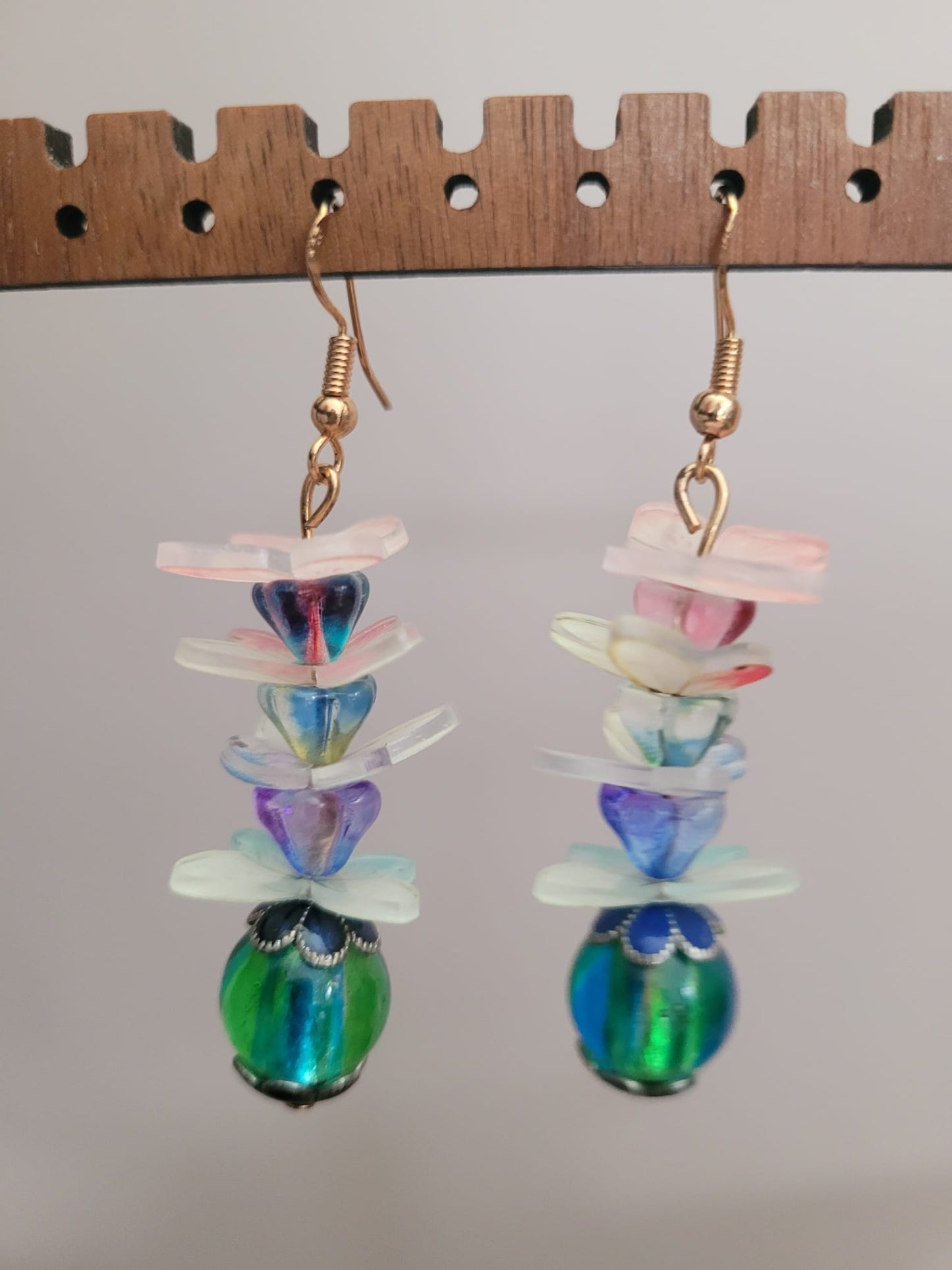 Colorful layered glass bead earrings on a wooden ruler for scale.