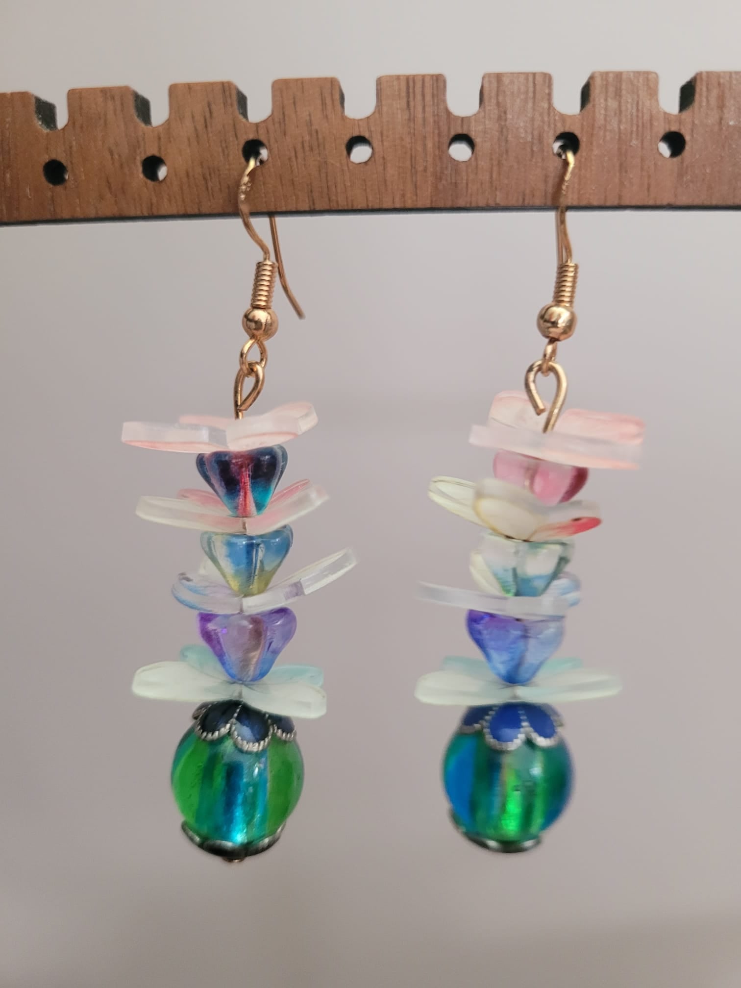 Colorful layered glass bead earrings on a wooden ruler for scale.